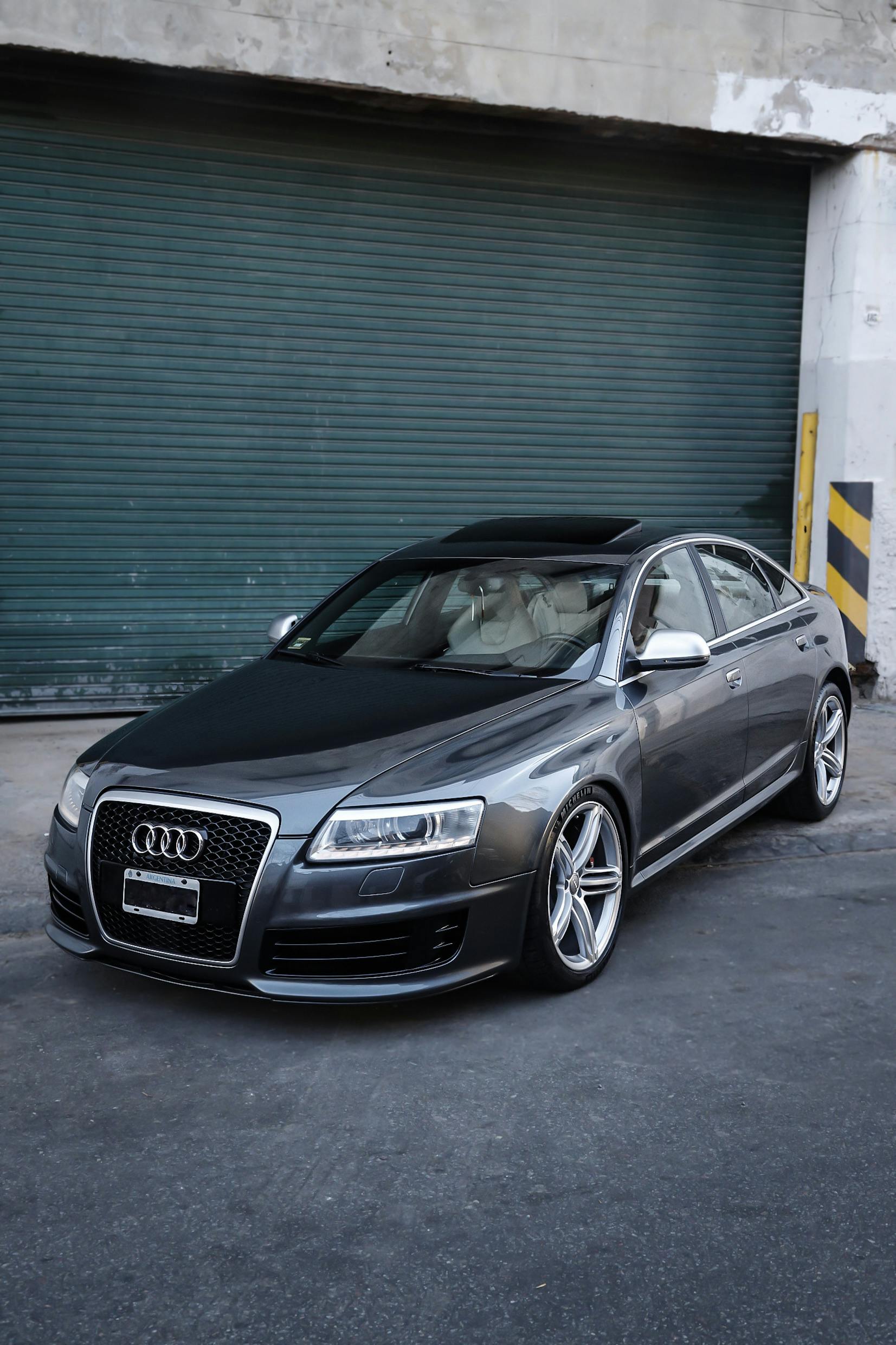 Modern black Audi sedan parked outside an industrial building, showcasing luxury design.